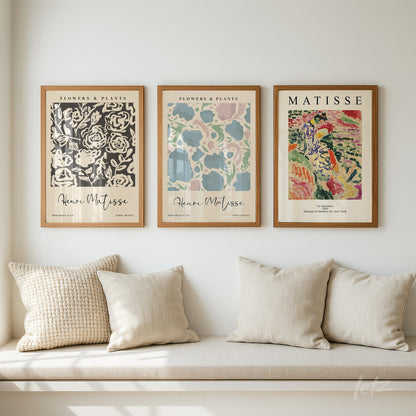 composição com três quadros decorativos de arte moderna em moldura de madeira clara, exibidos sobre um sofá com almofadas claras