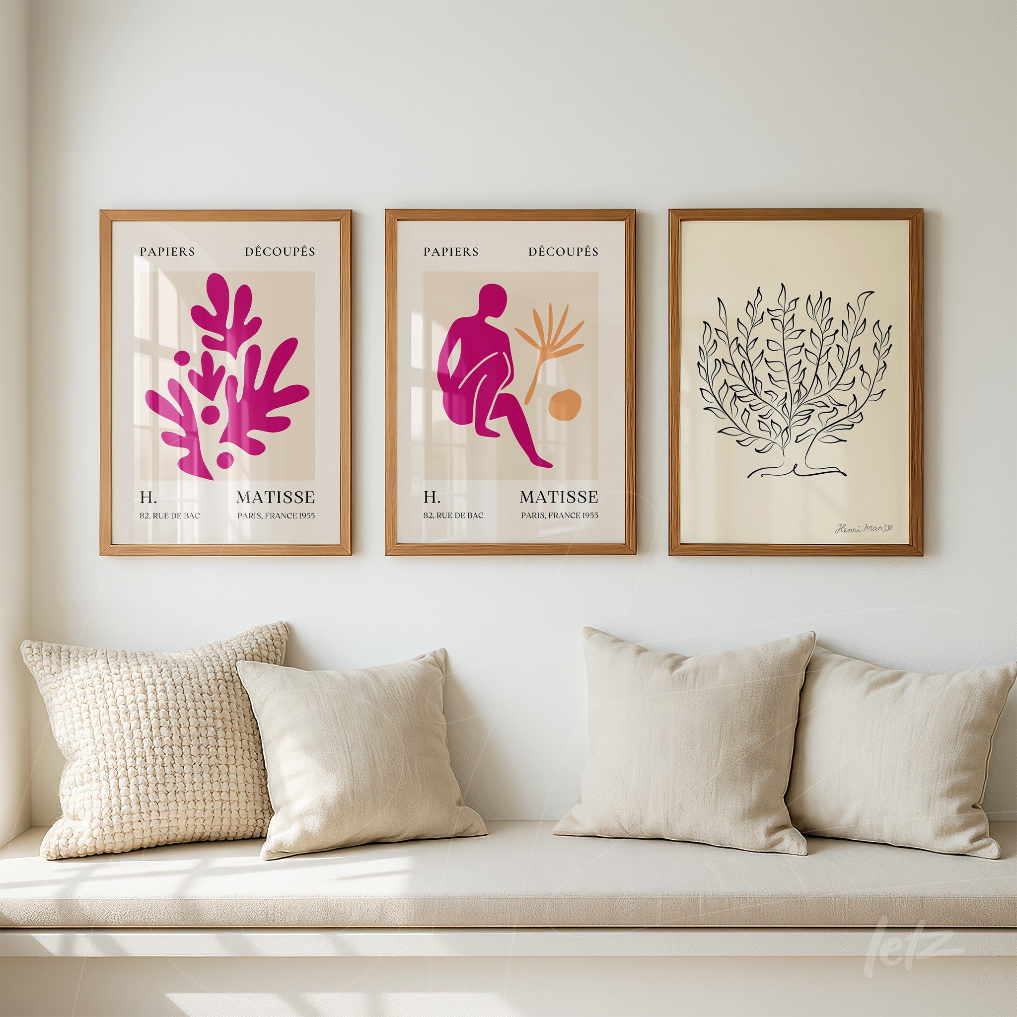 composição com três quadros decorativos em moldura de madeira clara, incluindo arte abstrata em rosa e roxo inspirada em Matisse e uma ilustração de folhas em preto