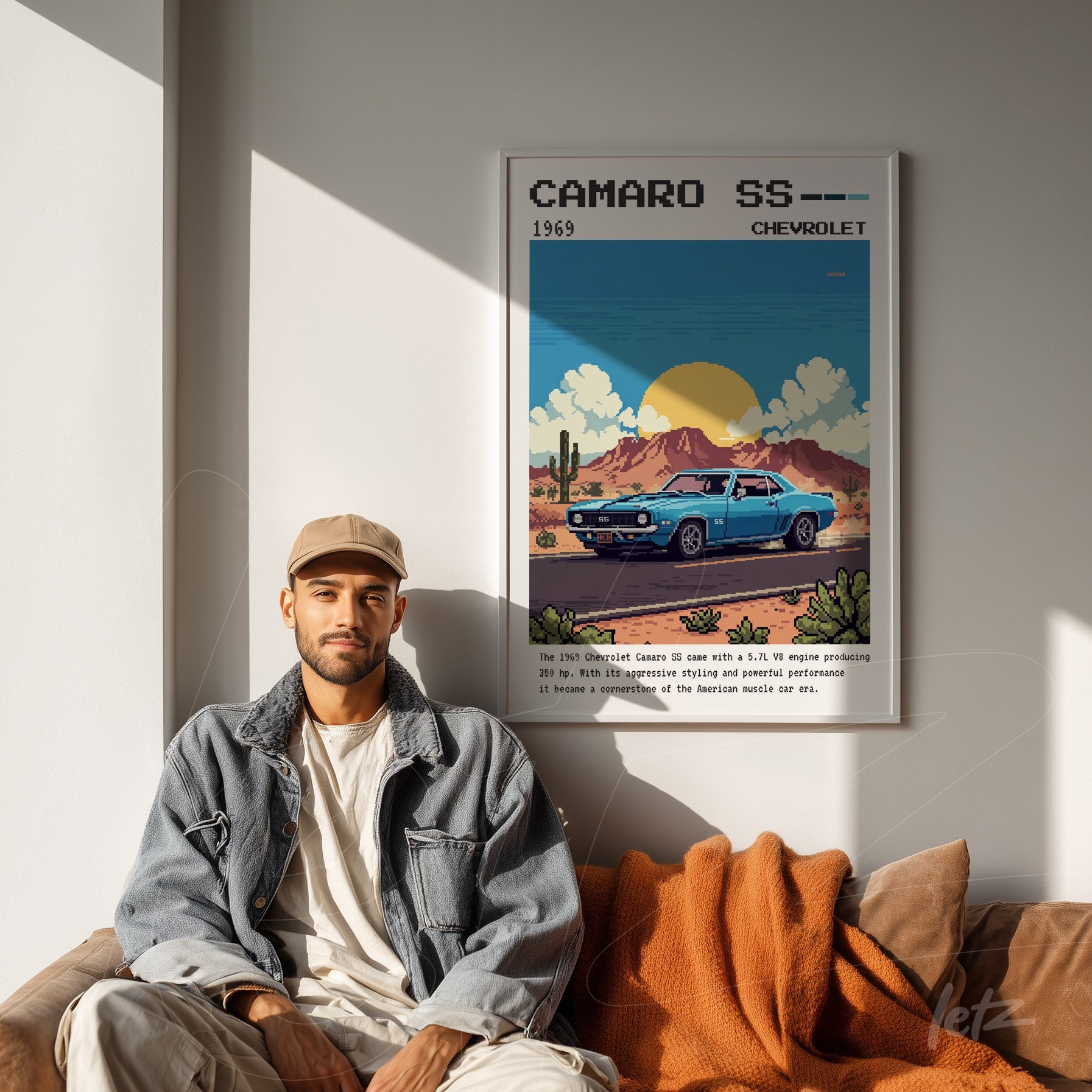 quadro com arte retrô de carro Camaro SS 1969 em moldura branca, exibido acima de um homem sentado em sofá com manta laranja