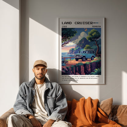 quadro emoldurado com ilustração vintage do Toyota Land Cruiser 1984, exibido em parede clara ao lado de um homem sentado em sofá com cobertor laranja