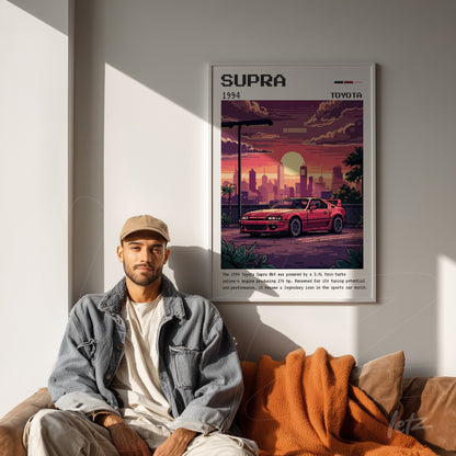 quadro decorativo retrô de carro Toyota Supra em moldura branca, exibido em ambiente moderno com sofá laranja