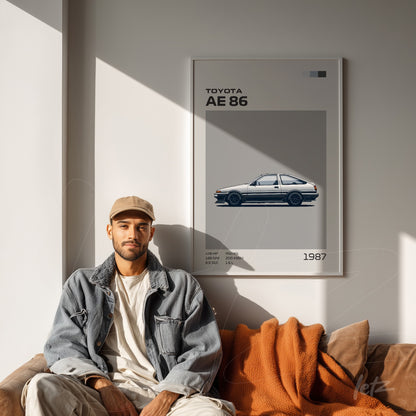 quadro decorativo com ilustração de um carro Toyota AE 86 em moldura branca, exibido em parede clara com um homem sentado ao lado