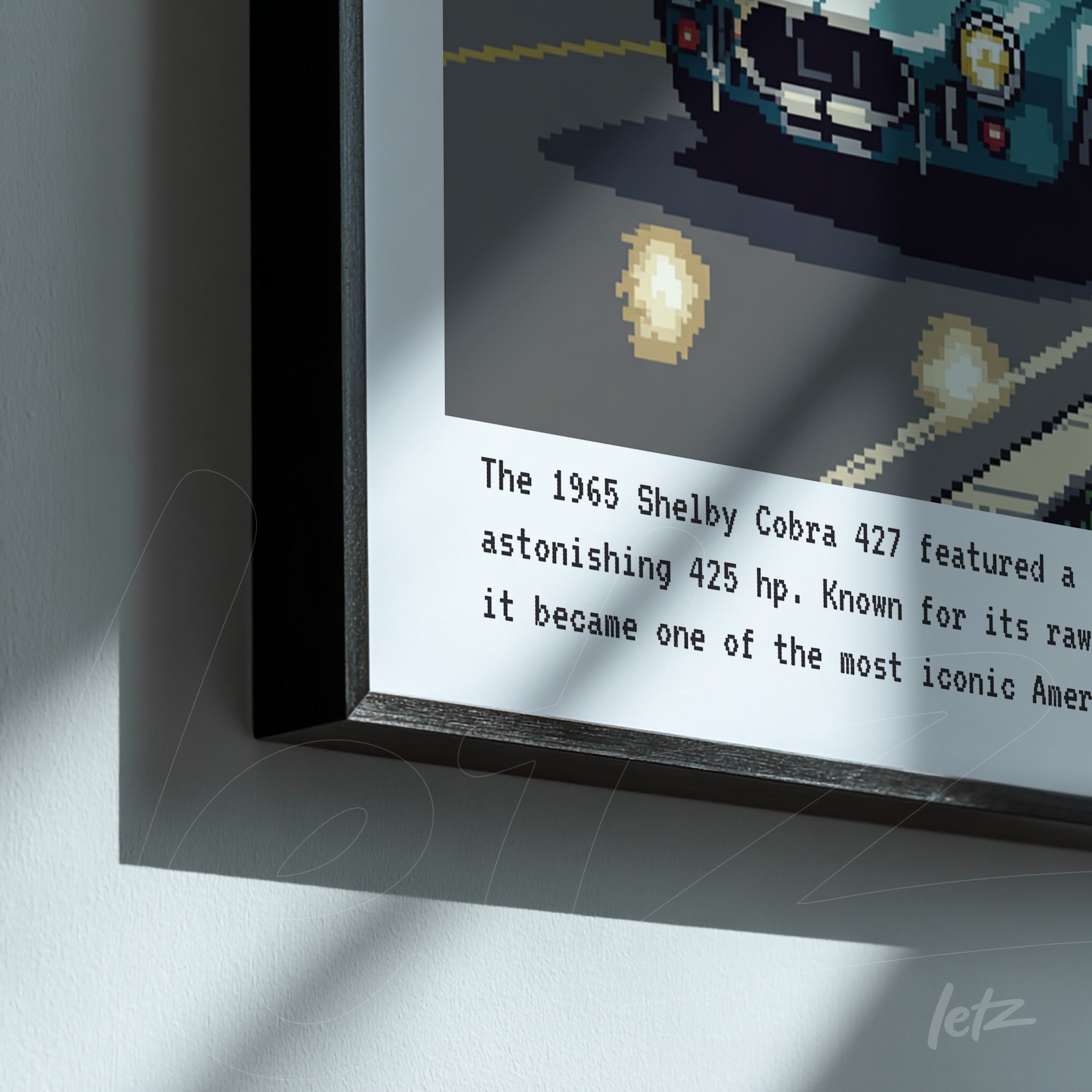 quadro com arte pixelada do carro Shelby Cobra 427 em moldura preta, com texto descritivo em fundo gris claro