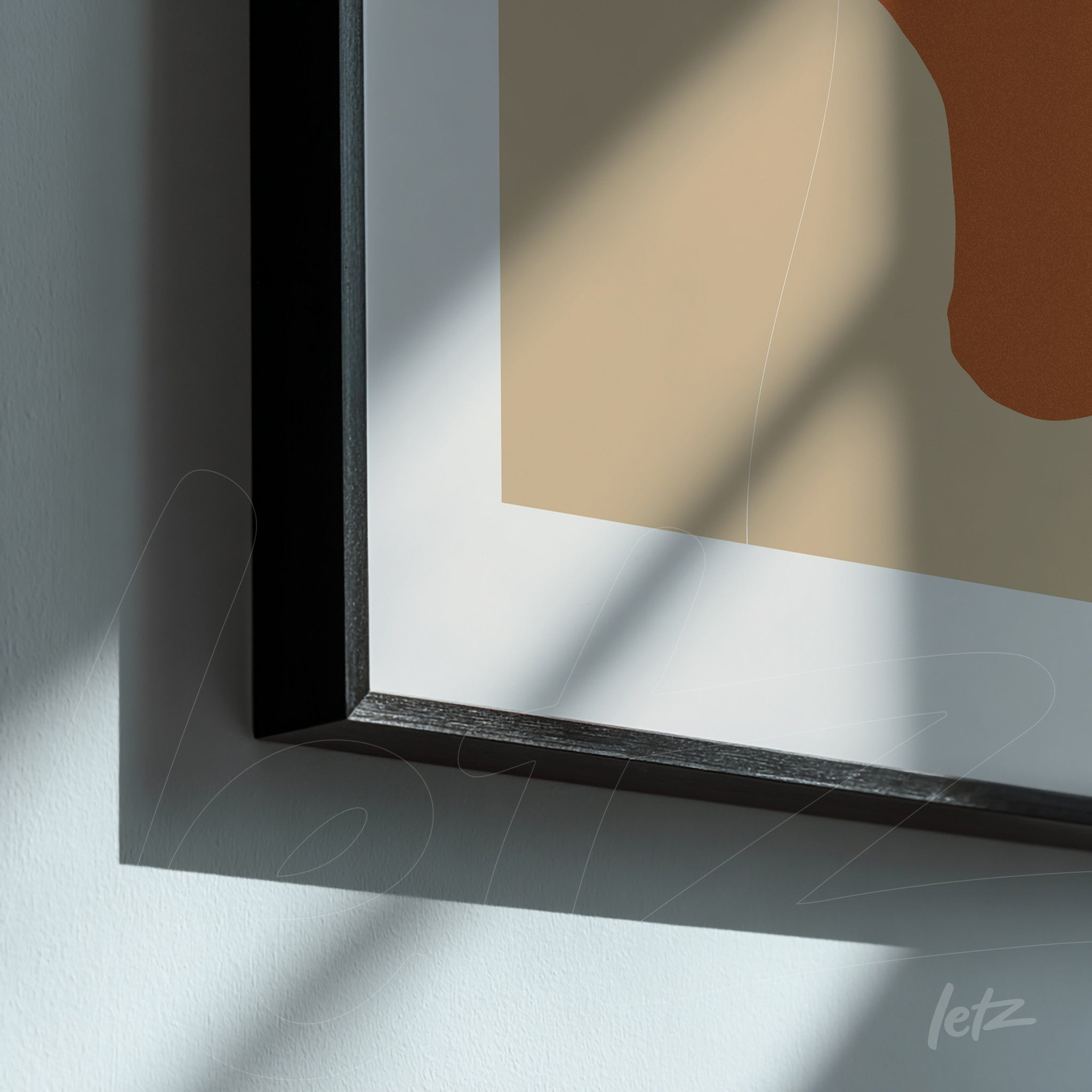 detalhe de arte minimalista em tons terrosos com moldura preta fina, luz natural criando sombras