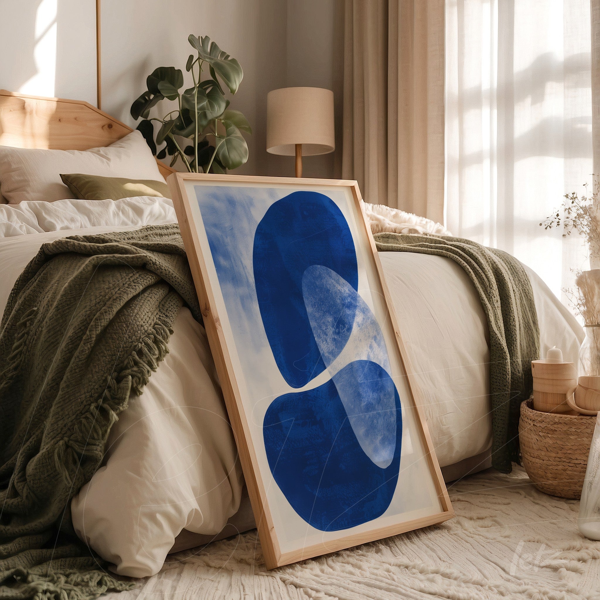 quadro emoldurado com arte abstrata em azul sobre fundo claro apoiado ao lado da cama em ambiente acolhedor