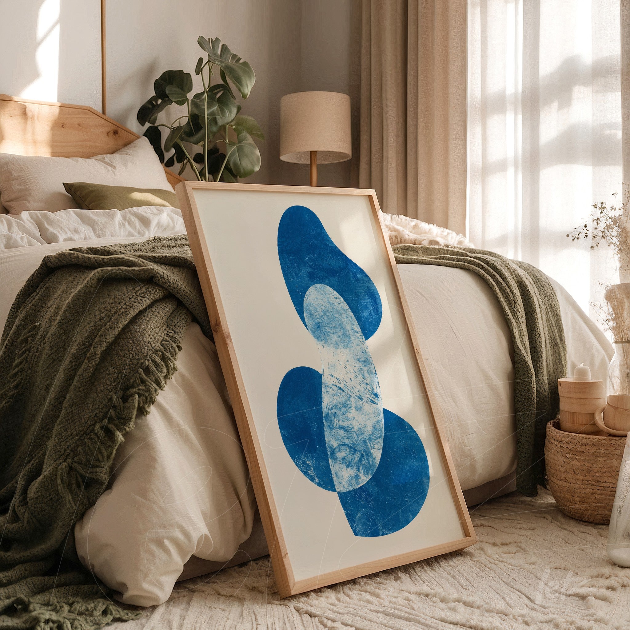 quadro com arte abstrata em tons de azul em moldura de madeira clara, apoiado ao lado de uma cama com roupa de cama branca e manta verde