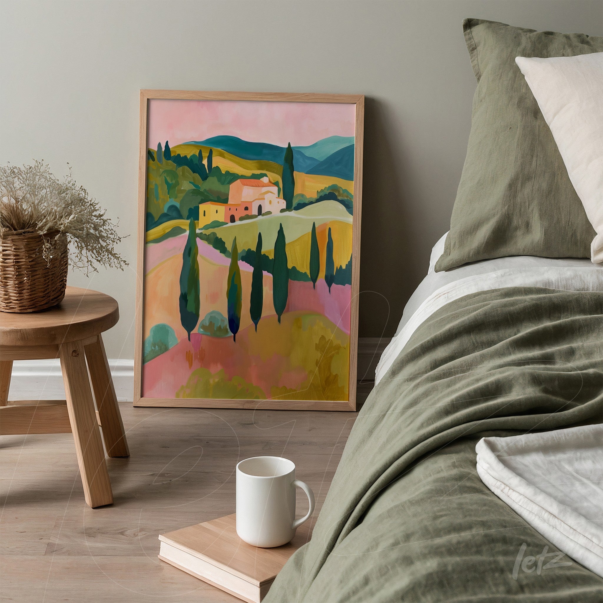 quadro com paisagem rural em tons vibrantes de rosa, verde e amarelo, em moldura de madeira clara, apoiado ao lado de uma cama com roupa de cama em tons neutros