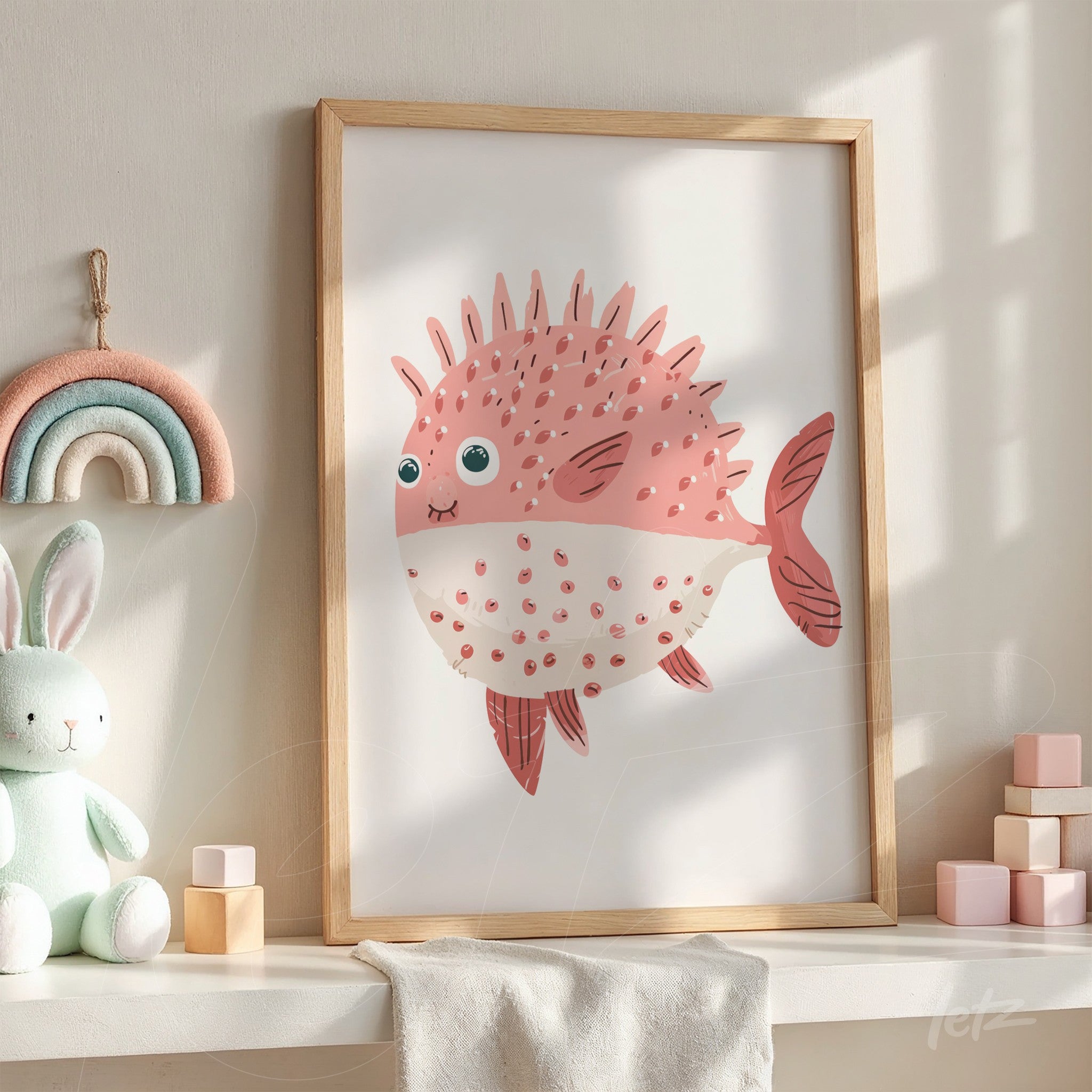 quadro com arte de peixe curioso em moldura de madeira clara apoiado sobre mesa com decoração infantil