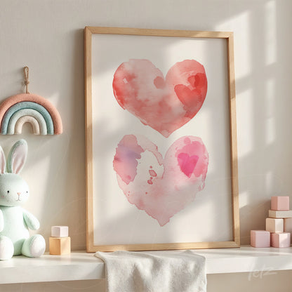 quadro decorativo com ilustrações em aquarela de corações em tons de rosa e vermelho, em moldura de madeira clara, exposto sobre móvel ao lado de brinquedos infantis