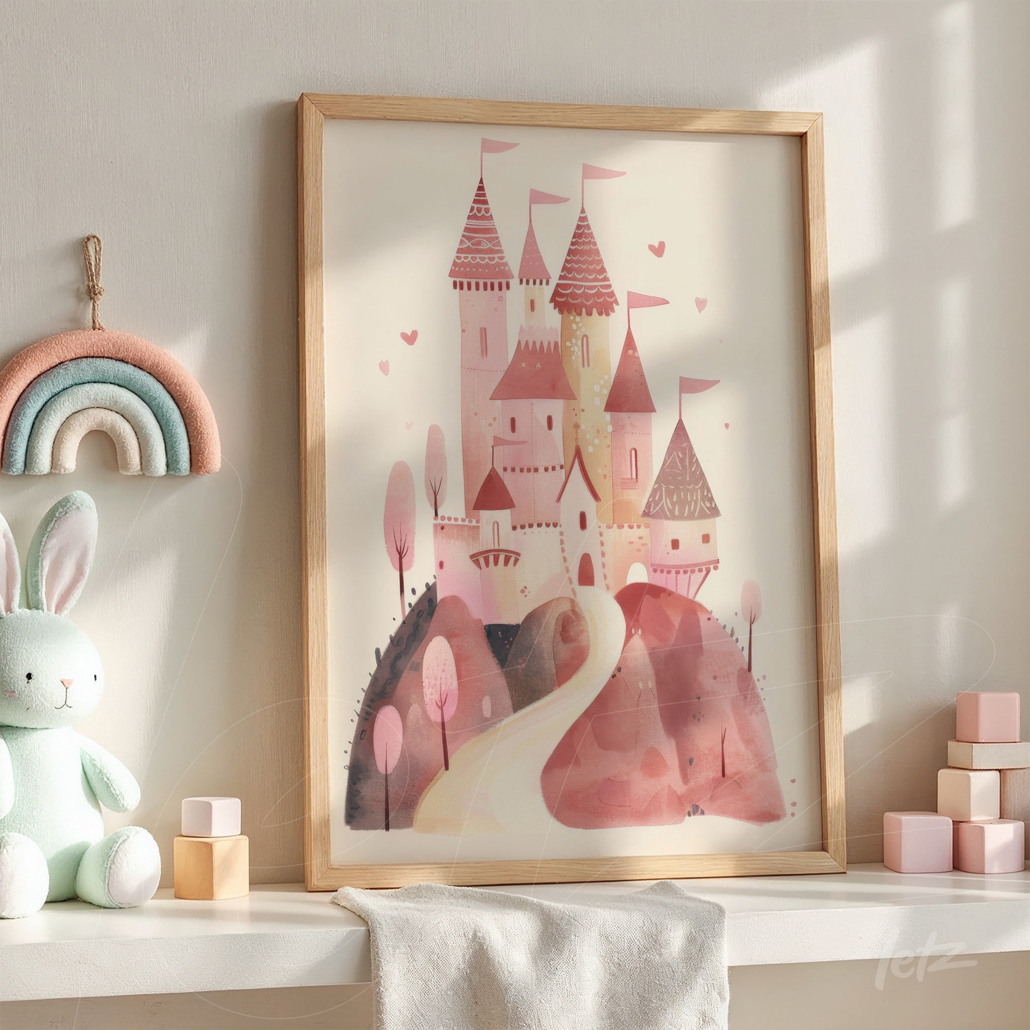 quadro emoldurado com ilustração de castelo rosa em estilo aquarela, apoiado em prateleira com brinquedos infantis e decorado com arco-íris de feltro