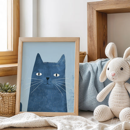 quadro com ilustração de gato azul em moldura de madeira clara, apoiado em sofá com almofadas e brinquedos de pelúcia