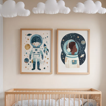 composição de dois quadros decorativos com ilustrações de astronautas em molduras de madeira clara, exibidos sobre um berço em ambiente infantil