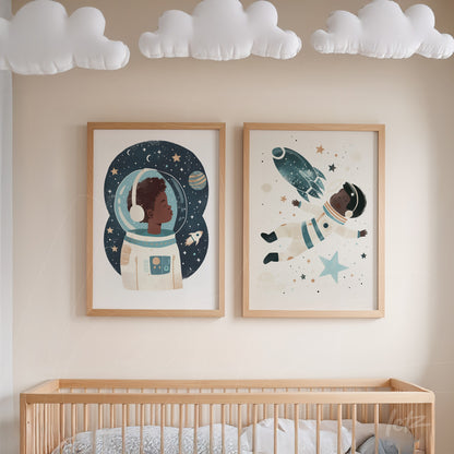 composição de quadros com ilustrações de astronautas em moldura de madeira clara, exibidos sobre berço em ambiente de quarto infantil