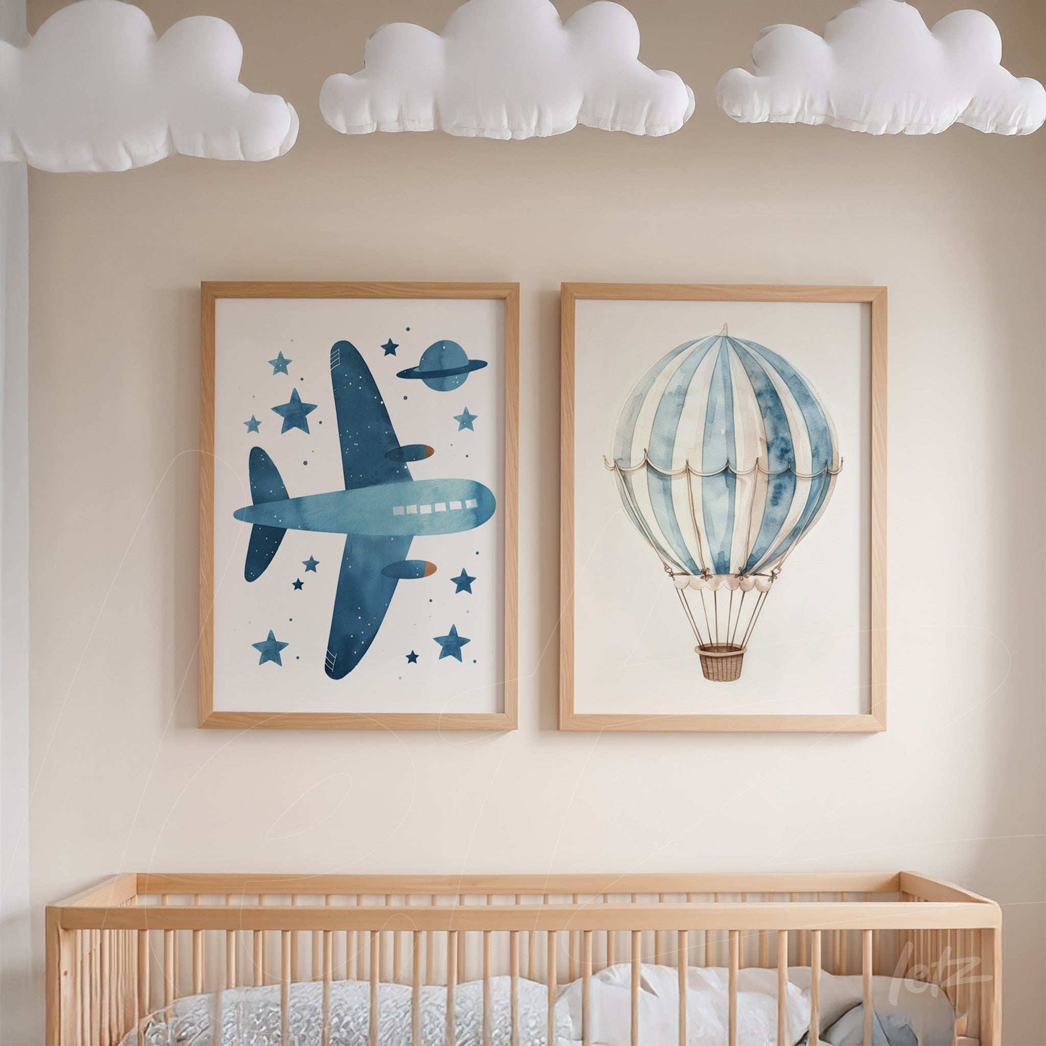 composição de quadros decorativos com ilustrações de avião azul e balão de ar quente em moldura de madeira clara, exibidos sobre berço em ambiente infantil