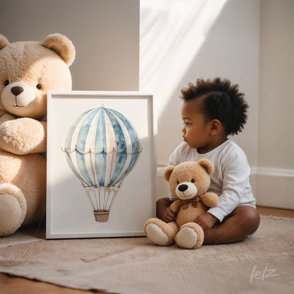 quadro com ilustração de balão de ar quente em moldura branca, exibido ao lado de uma criança sentada com brinquedo de ursinho