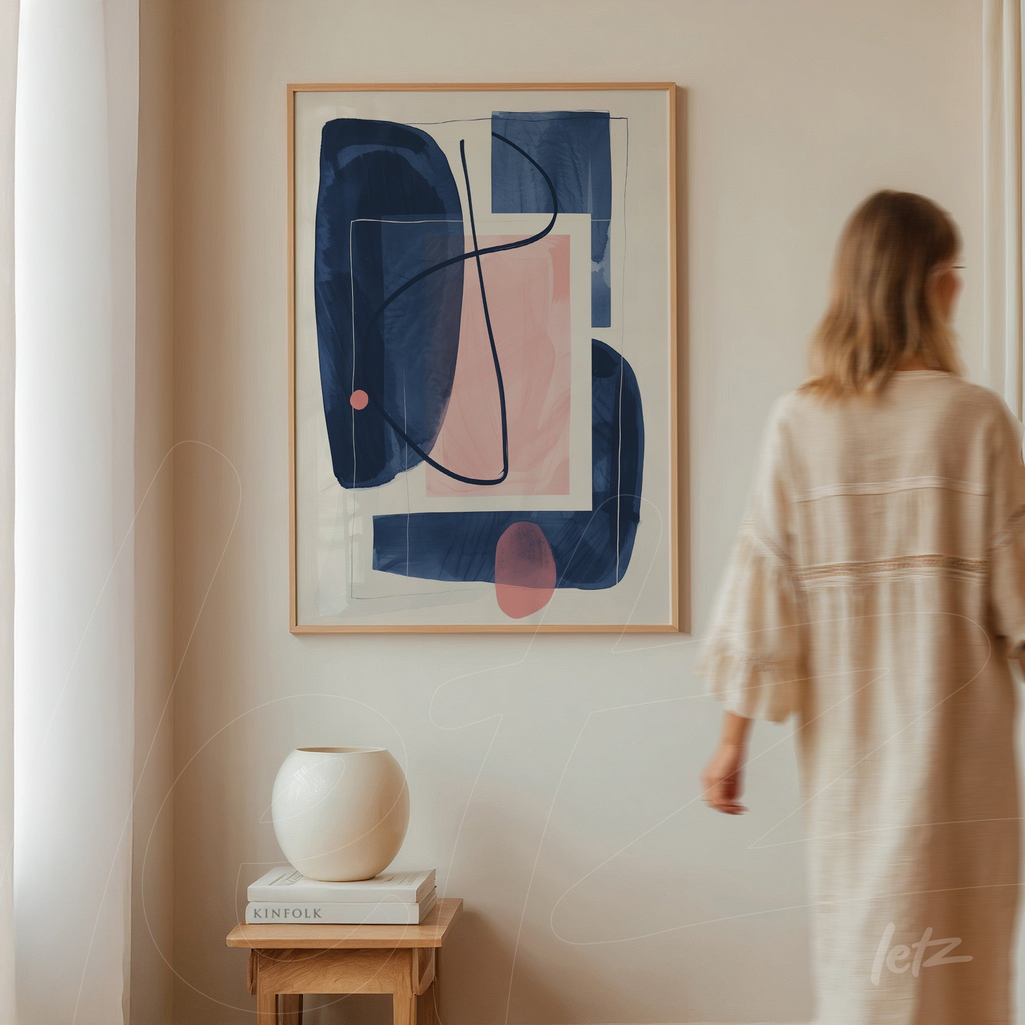 quadro com arte abstrata em moldura clara exibido em parede neutra com uma mulher ao fundo em movimento