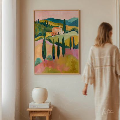 quadro com paisagem vibrante de colinas e ciprestes em moldura clara, exibido em parede de ambiente neutro com vase decorativo ao lado