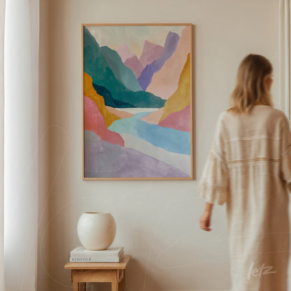 quadro com arte abstrata de paisagem montanhosa em moldura clara, exposto em parede neutra com pessoa ao fundo