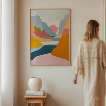 quadro com paisagem abstrata em moldura clara, exibindo montanhas coloridas e um lago sereno em tons de rosa, amarelo e azul