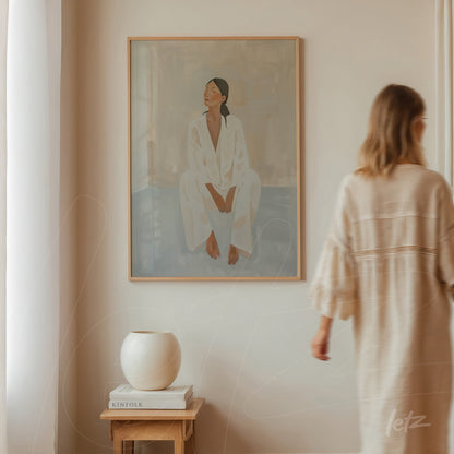 quadro com retrato minimalista de mulher vestindo roupa branca em moldura de madeira clara exibido em parede clara