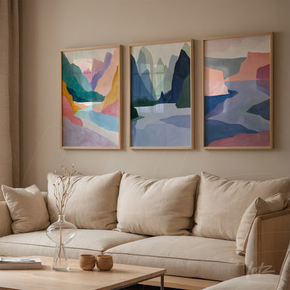composição com três quadros de arte abstrata em moldura clara, exibindo montanhas e formas geométricas em tons suaves de azul, rosa e verde sobre parede de tom neutro
