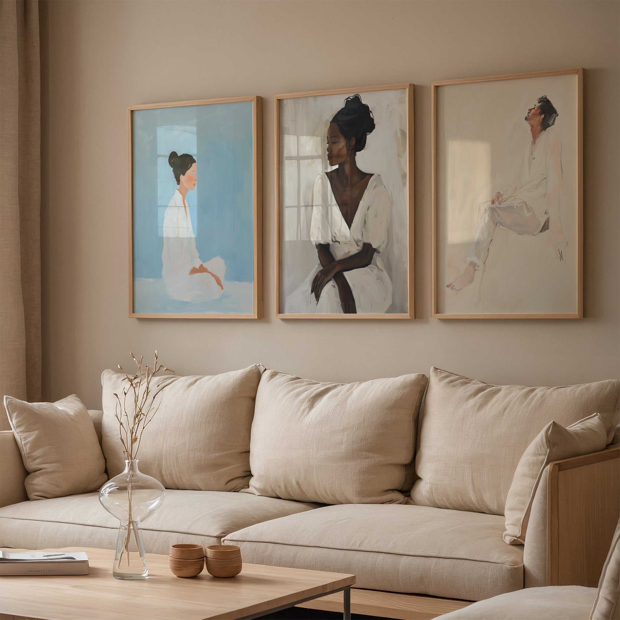 composição de três quadros com retratos artísticos em moldura de madeira clara sobre parede bege, exibidos acima de sofá neutro