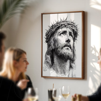 quadro emoldurado retratando a face de Cristo com coroa de espinhos, exibido em parede clara, com pessoas ao fundo em um ambiente de confraternização