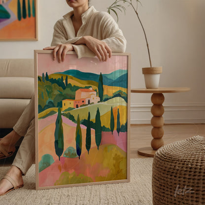 quadro decorativo com paisagem campestre em cores vibrantes, moldura clara, exposto em ambiente aconchegante com sofá e mesa de madeira