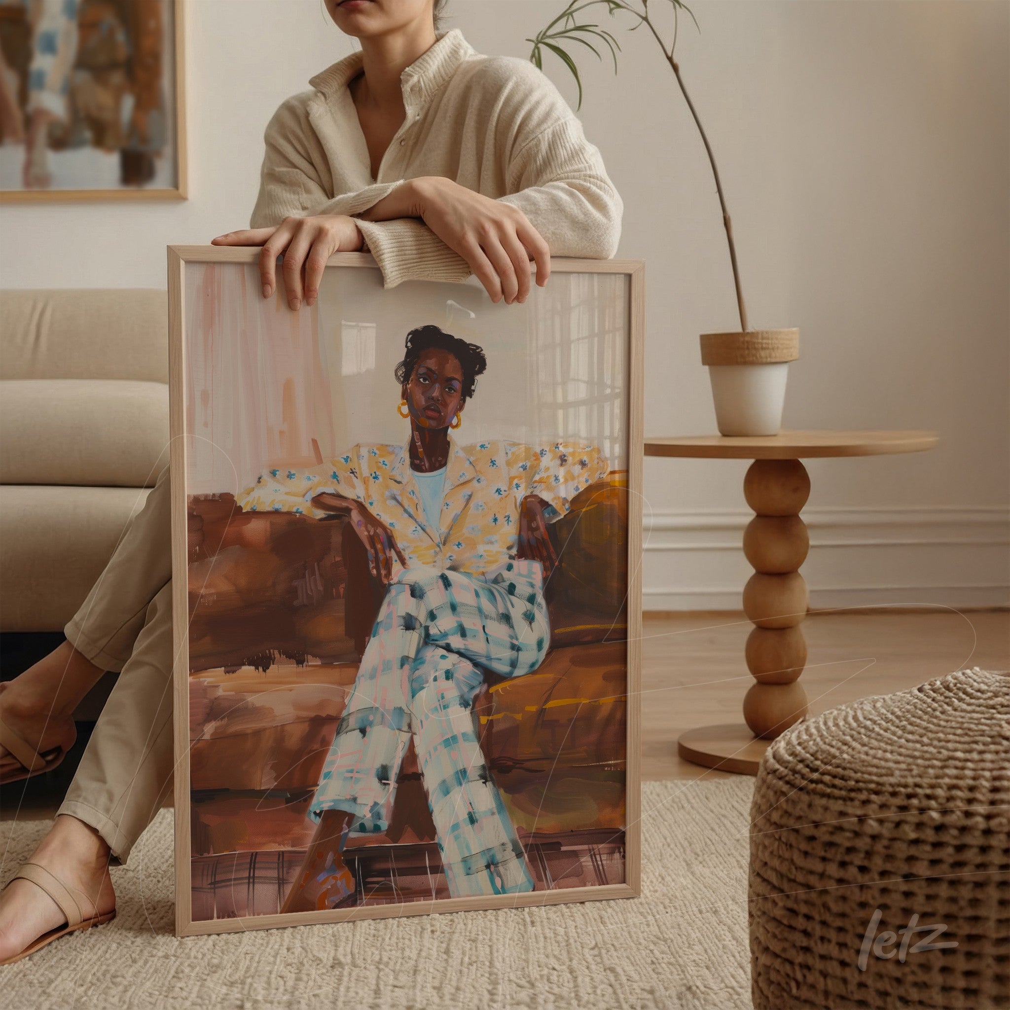 quadro em moldura de madeira clara com retrato de mulher negra vestindo blusa de bolinhas e calças xadrez, apoiado em mesa redonda