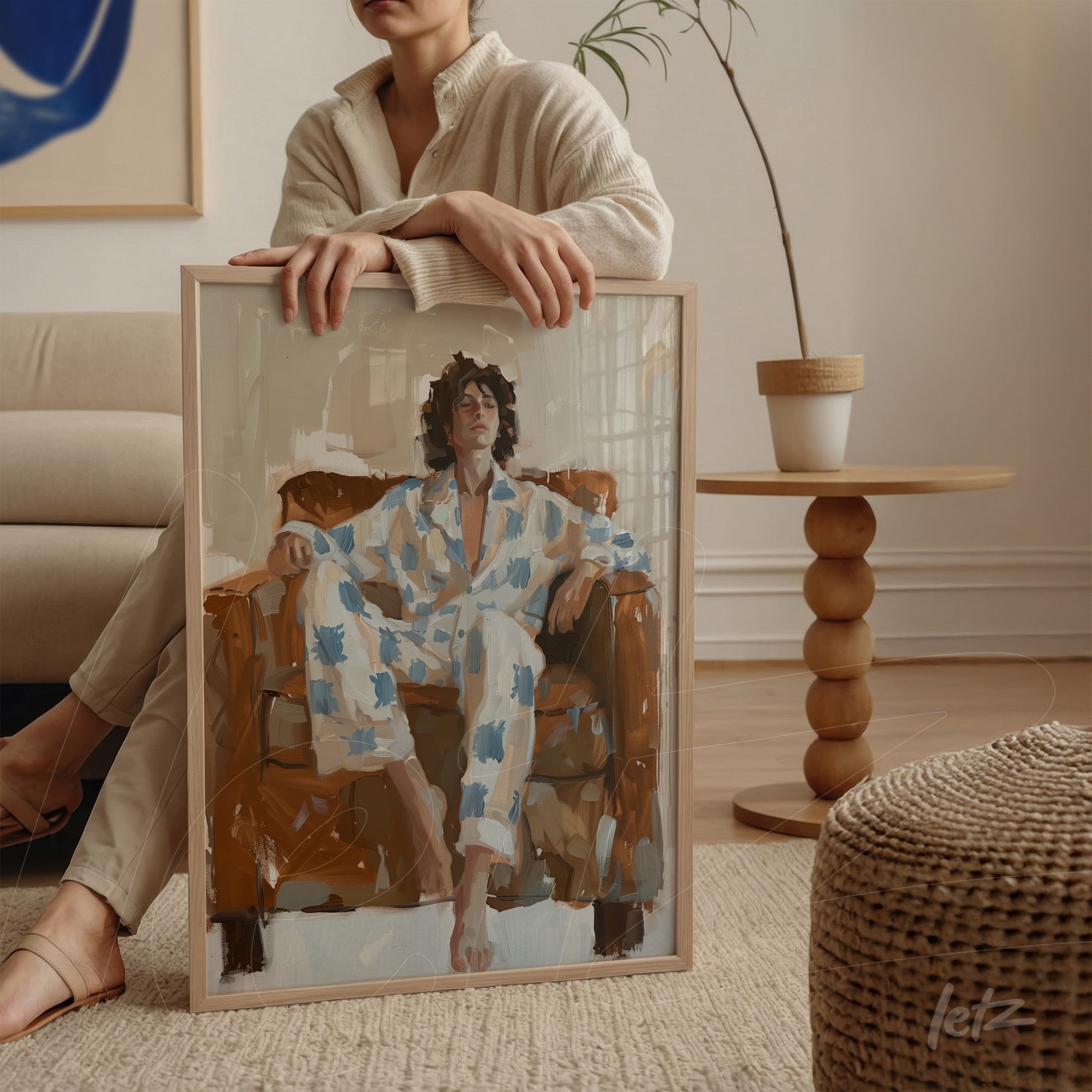 quadro com arte contemporânea retratando mulher relaxando em cadeira marrom, moldura clara e fundo neutro