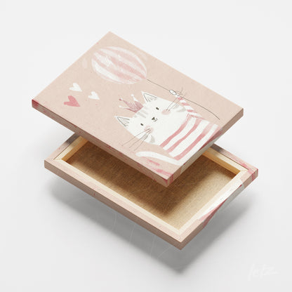 quadro em canvas com ilustração de gato fofo usando uma camiseta listrada e segurando um balão, fundo rosa suave