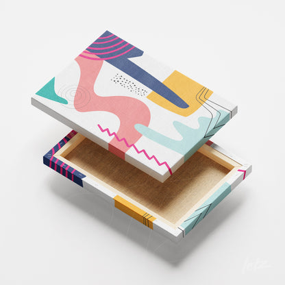 arte em canvas de estilo abstrato geométrico com formas coloridas e traços curvos exibida em ângulo sobre fundo branco