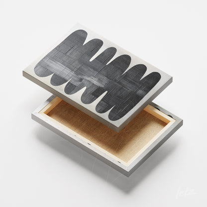 foto de quadro em canvas apresentando formas abstratas em preto e branco, vista superior com fundo claro