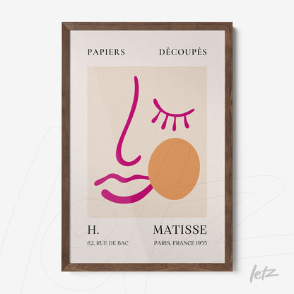 quadro com arte moderna de uma face estilizada em tons rosa e laranja, moldura de madeira escura, fundo creme