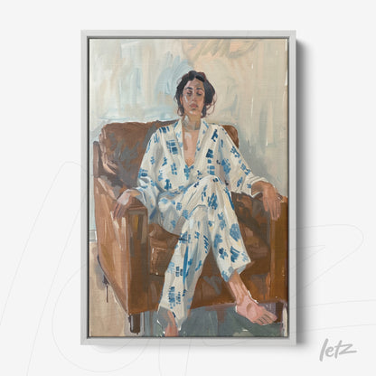 quadro com retrato de mulher sentada em sofá marrom, vestindo pijama com padrão azul em fundo claro, emoldurado com moldura branca