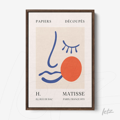 quadro com arte moderna de rosto estilizado em moldura marrom, apresentando cores vibrantes como azul e vermelho sobre fundo claro