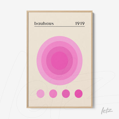 quadro com círculos concêntricos em tons de rosa sobre fundo bege com texto bauhaus 1919 em moldura de madeira clara