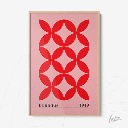 pôster com arte geométrica em vermelho sobre fundo rosa emoldurado em madeira clara com texto referenciando bauhaus 1919